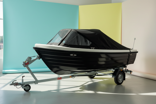 Marinaut 480 sloep met zwarte romp, witte kuip en zwarte buiskap op trailer, klaar voor gebruik op het water. Uitgerust met HPL teak en gewatteerde kussenset.